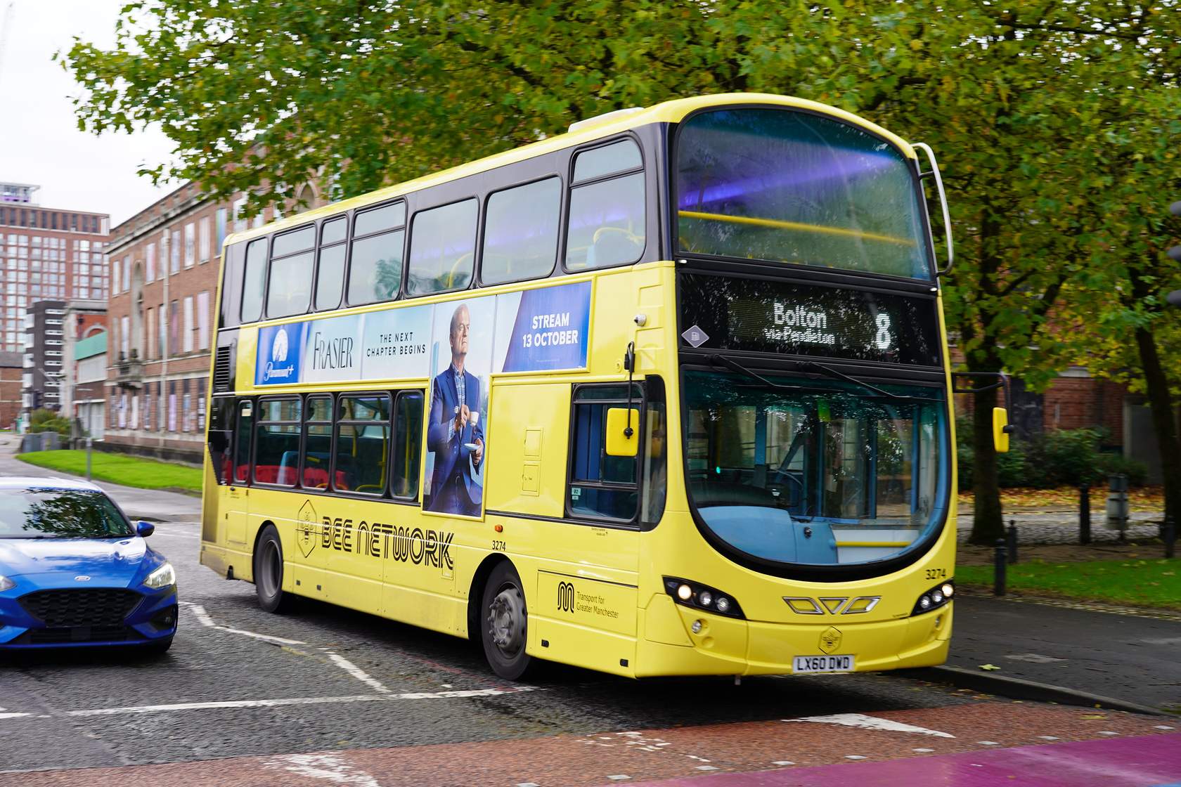 A yellow Bee Network bus waiting at a road crossing.