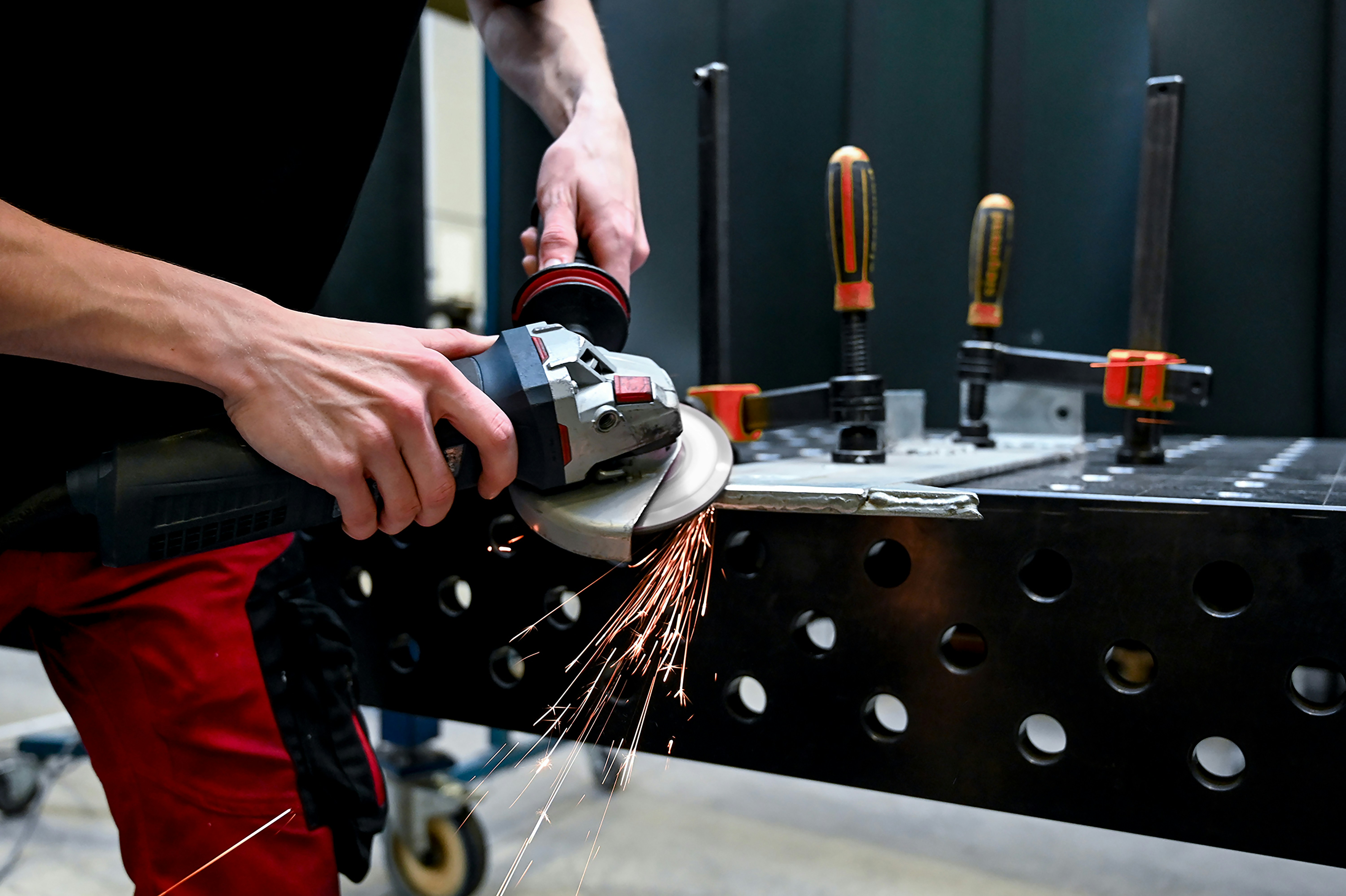A person creates sparks using an angle-grinder against a steel fabrication.