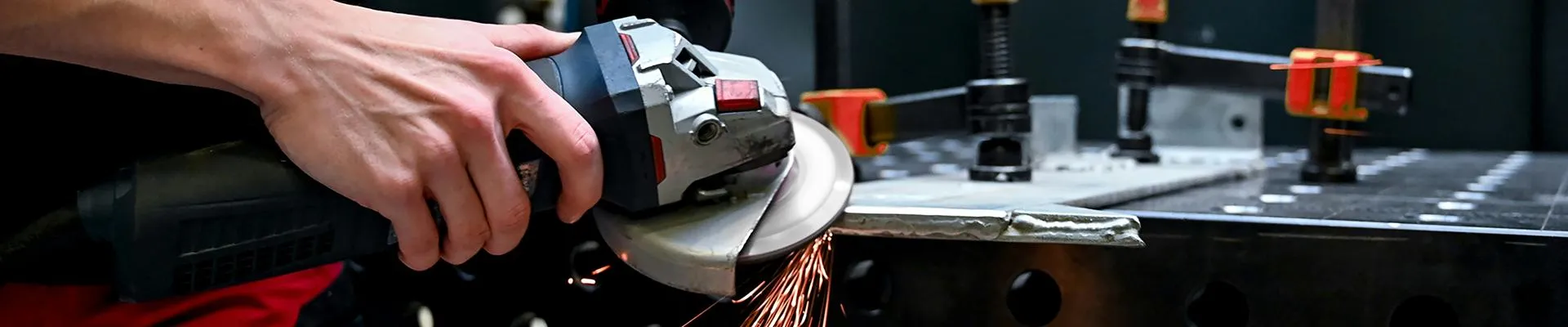 A person creates sparks using an angle-grinder against a steel fabrication.