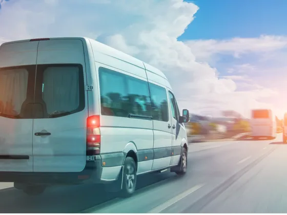 A white mini bus travelling along a road with other traffic.