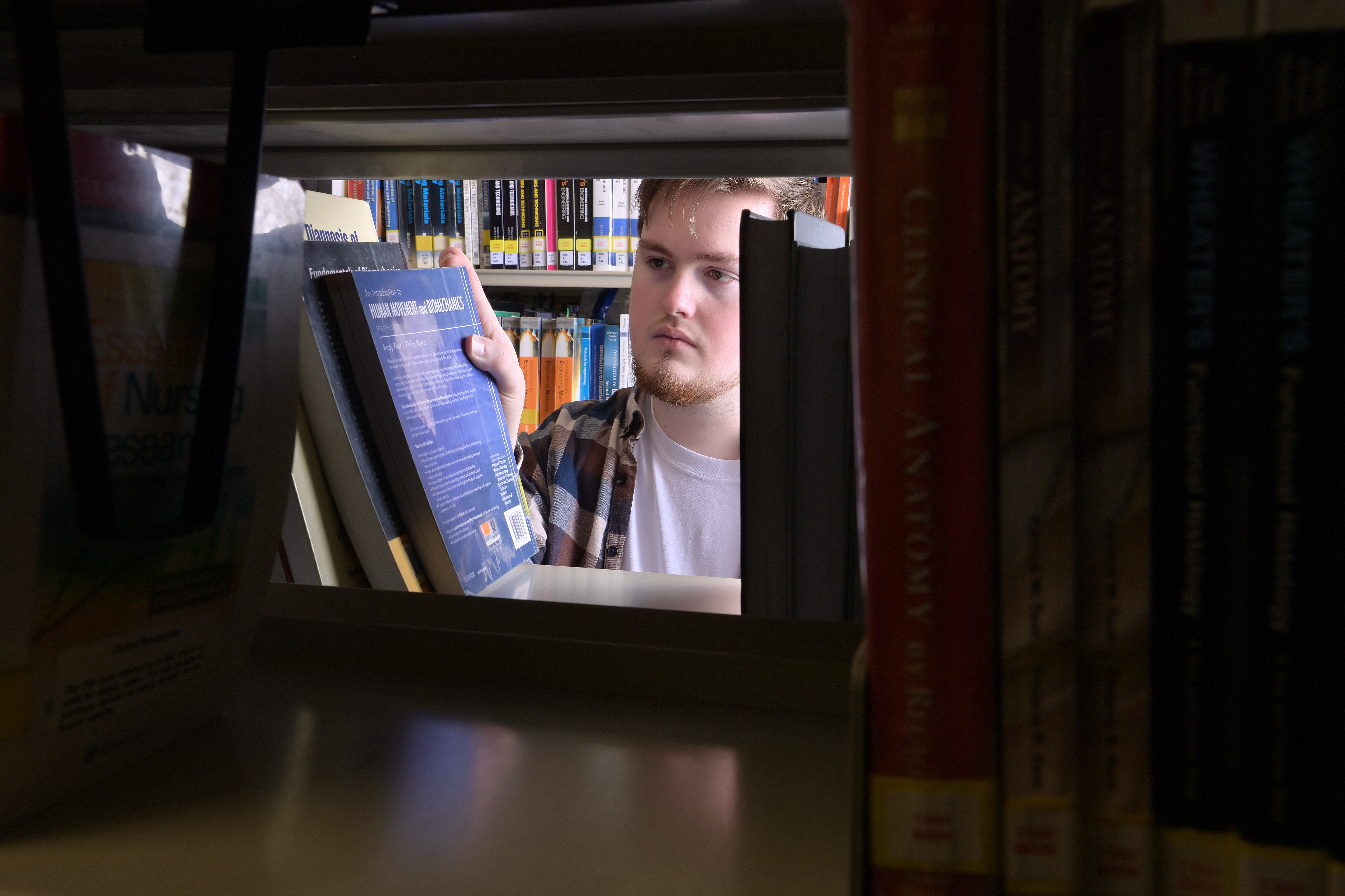 Student taking book from library shelf