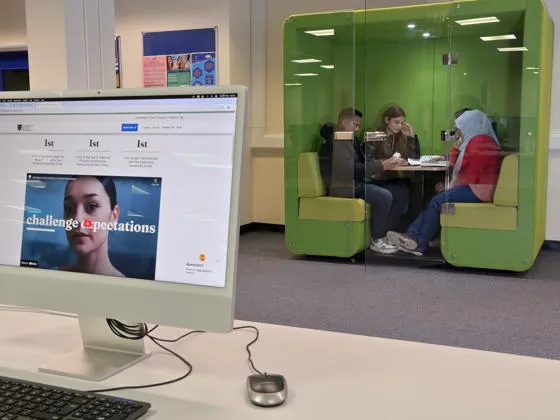 A modern library with study pod occupied by students studying as a group.