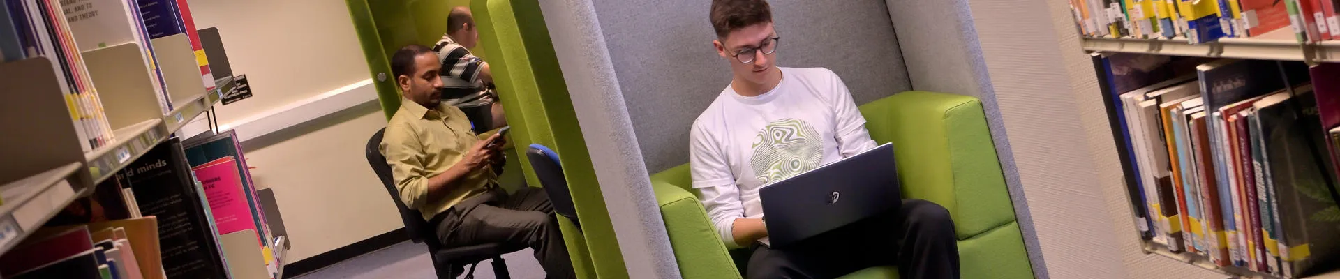 Student sat in a study pod using a laptop computer.
