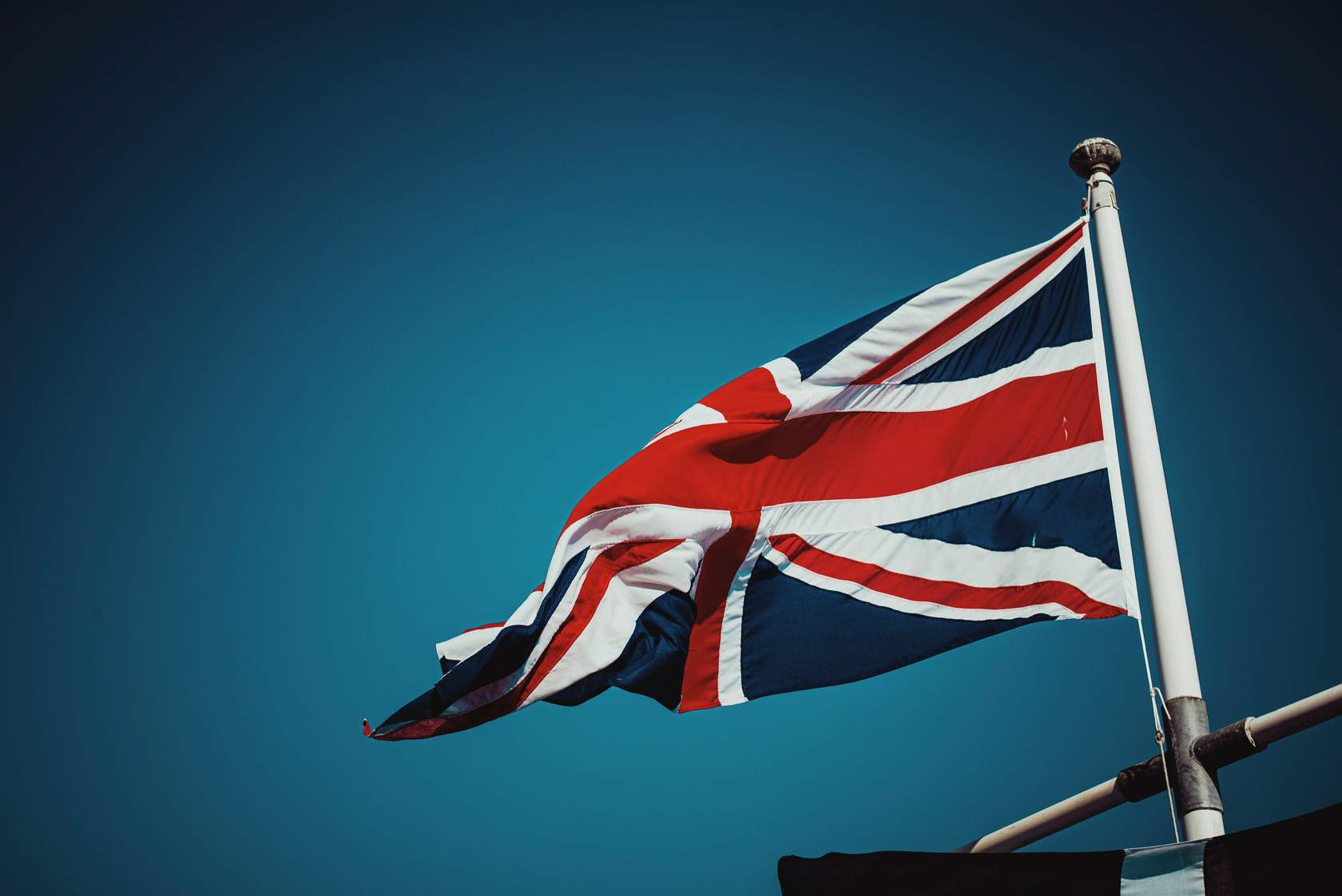 Union flag flying from flag pole against a clear blue sky